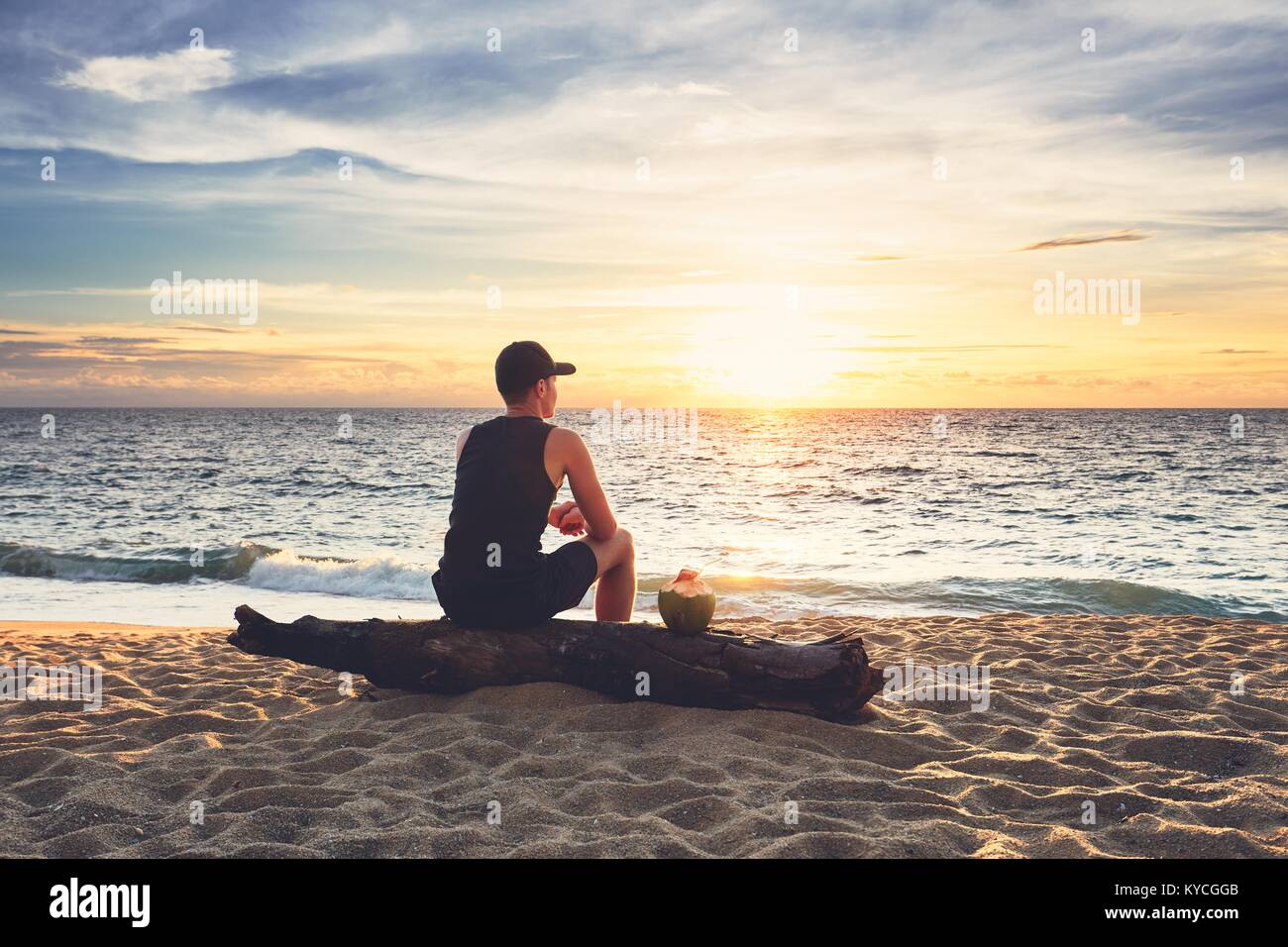 Nachdenklicher junger Mann mit Kokosnuss Drink relaxen am Strand bei ...