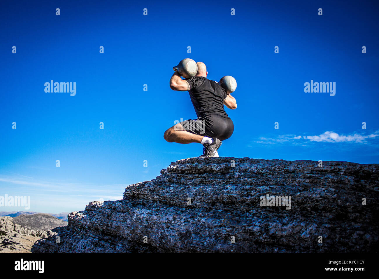 Mann mit zwei Kettlebells mit Blick auf Landschaft Stockfoto