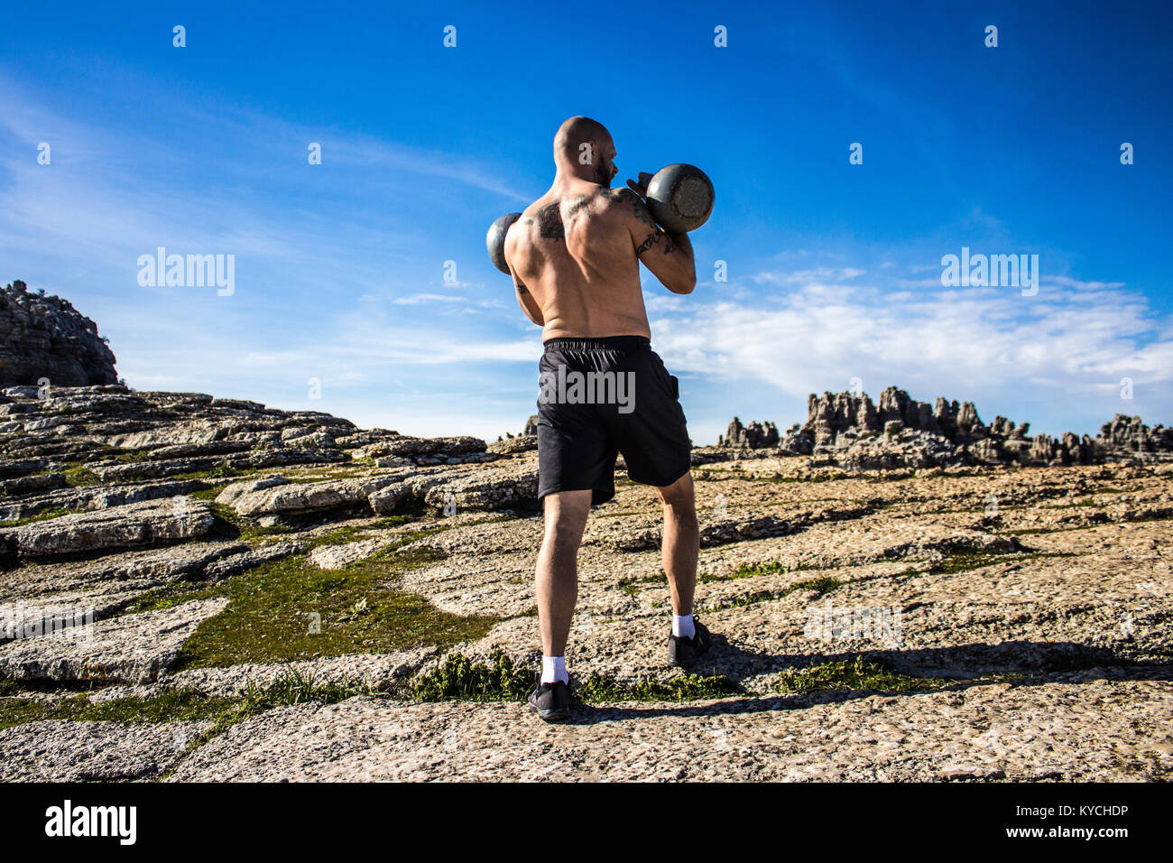 Kettlebell Trainer in den Bergen mit zwei Kettlebells Stockfoto