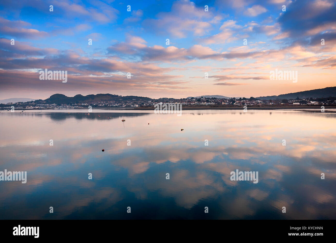 Blick von Conwy über den Fluss zu Deganwy mit Fluffy Clouds spiegelt sich im Wasser Stockfoto