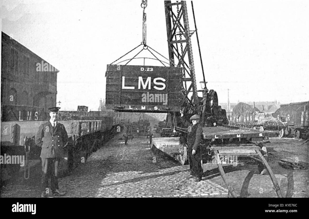 Das Foto von CJ Allen’s The Steel Highway (1928) zeigt Frachtcontainer, die auf der London, Midland & Scottish Railway zwischen LKW und Eisenbahnwaggon transportiert werden, was die frühe intermodale Containerlogistik veranschaulicht. Wikimedia Commons+1 Stockfoto