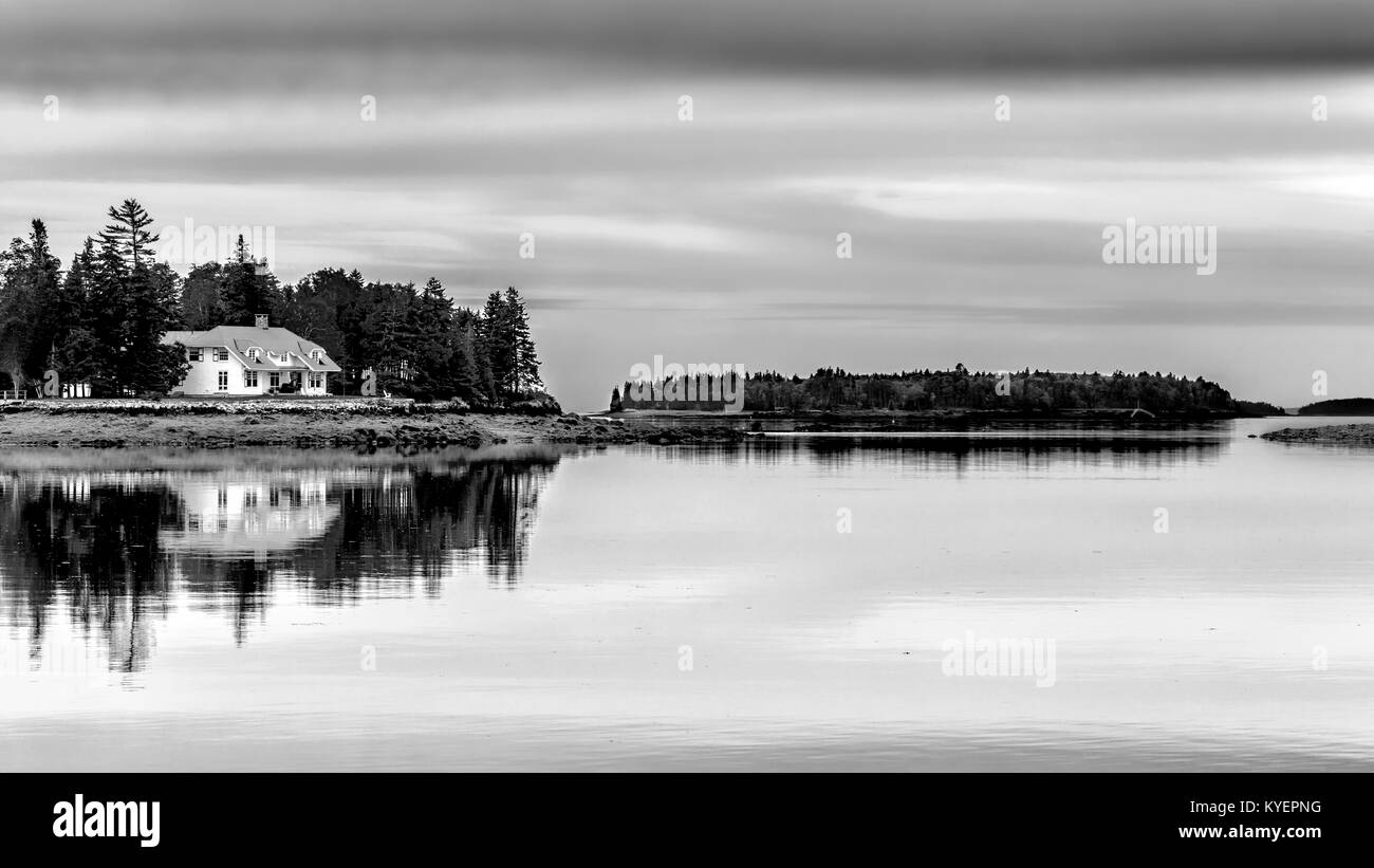 Kleine Insel mit Haus und Reflexionen in gläsernen Wassers. Ort: Maine USA. Penobscot Bay. Schwarze und weiße Schwarzweißbild. Platz kopieren Stockfoto