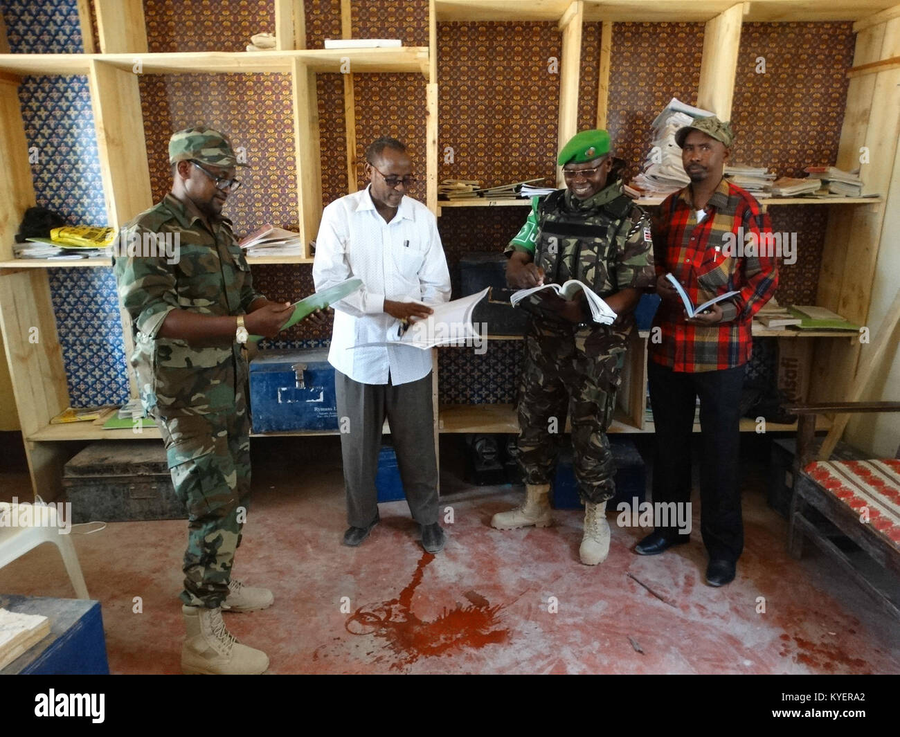 Kenianische Soldaten, als Teil der Mission der Afrikanischen Union in Somalia, stehen neben den Schreibtisch an die Wamo Primary und Secondary School in Dhobley, Somalia gespendet. Regale, sowie Malen, wurden auch in der Schule, in dem sich rund 350 Studenten gespendet. Die AMISOM Foto Stockfoto