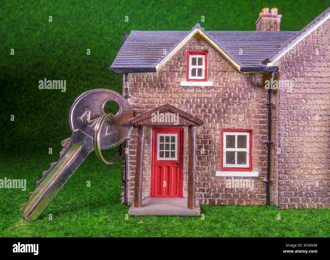 Schlüssel für die Tür gelehnt auf einem Modell Haus. Konzept, das sich auf home Besetzung, eg, Kauf/Verkauf/Vermietung/Verschieben/Hypothek. Stockfoto