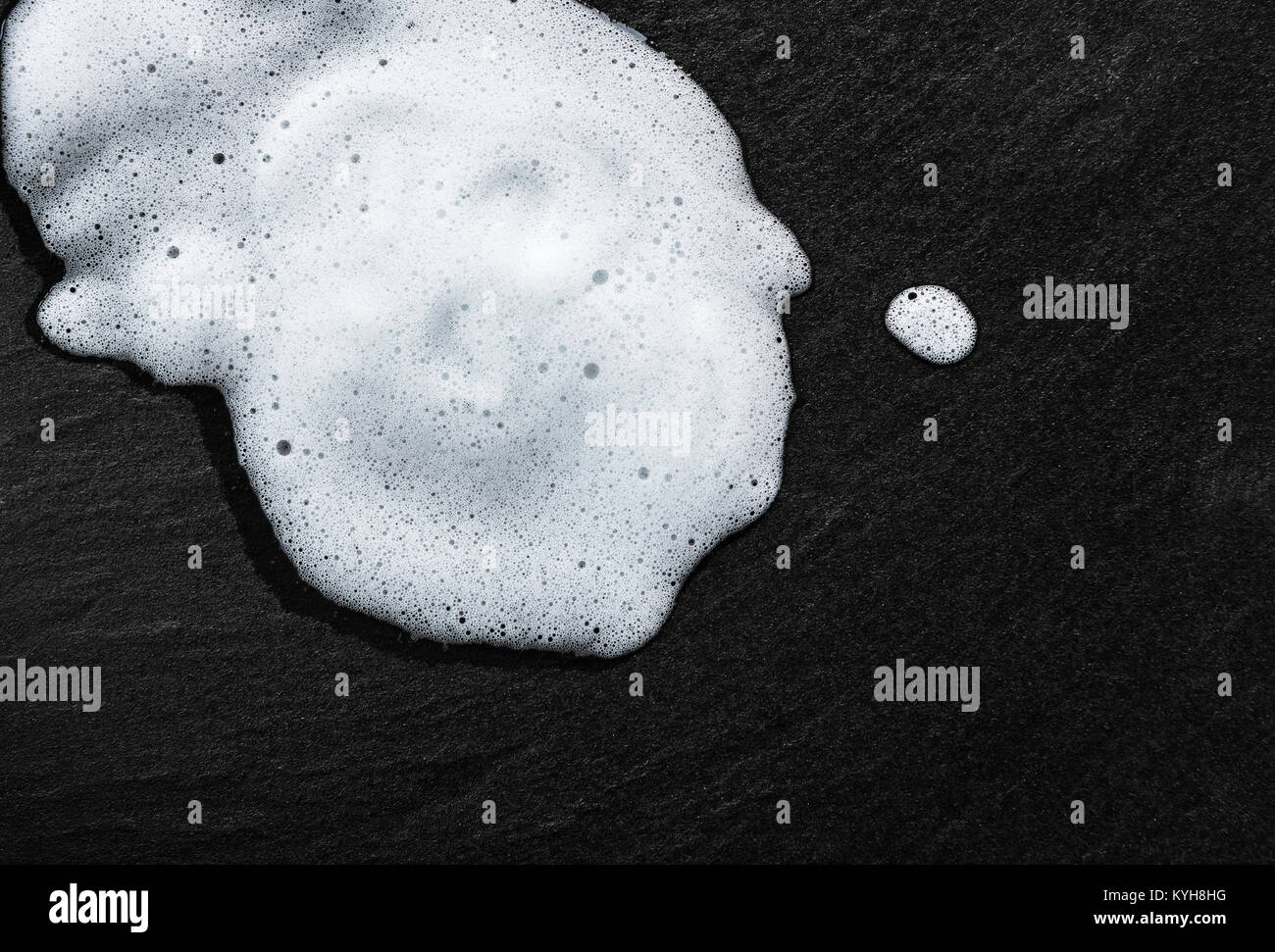 Weiss schaumige Seifenlauge auf Schwarze texturierte Bodenfliese, Blasen. Stockfoto