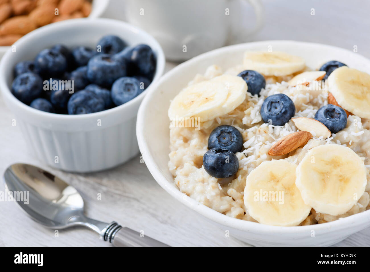 Porridge mit Banane, Blaubeere und Mandeln in weiße Schüssel. Detailansicht. Gesunde Ernährung, Diäten, Gewichtsabnahme Konzept Stockfoto