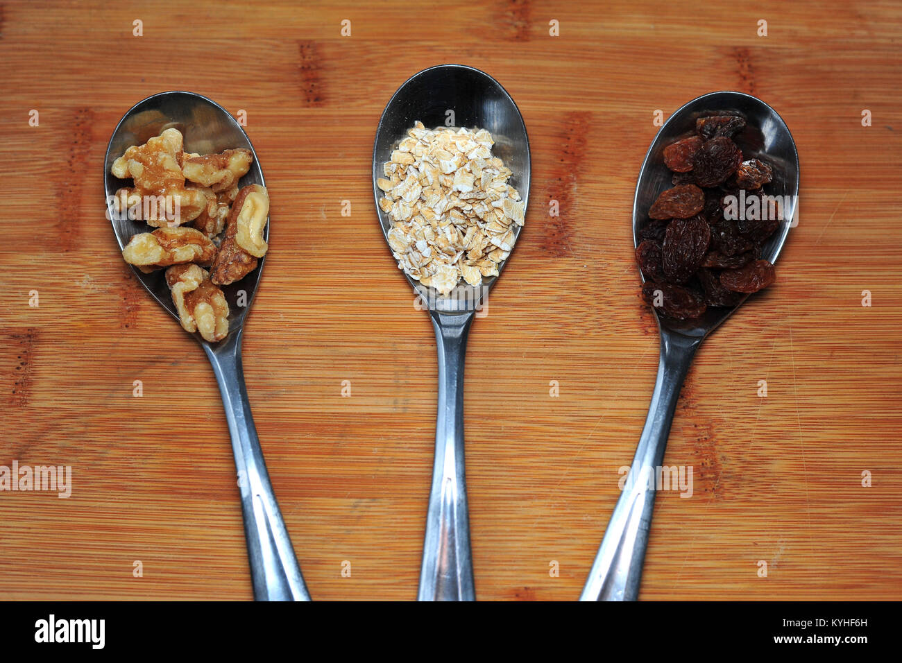 Drei Teelöffel mit Nüssen, Haferflocken und getrocknete Früchte. Stockfoto