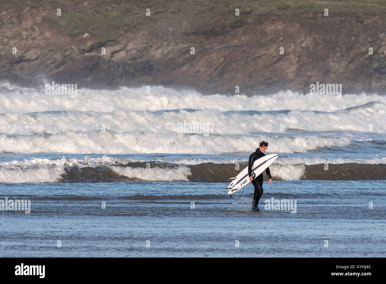 Polzeath surfen - ein müdes Surfer zu Fuß aus dem Meer auf Polzeath Strand an der Küste von North Cornwall. Stockfoto