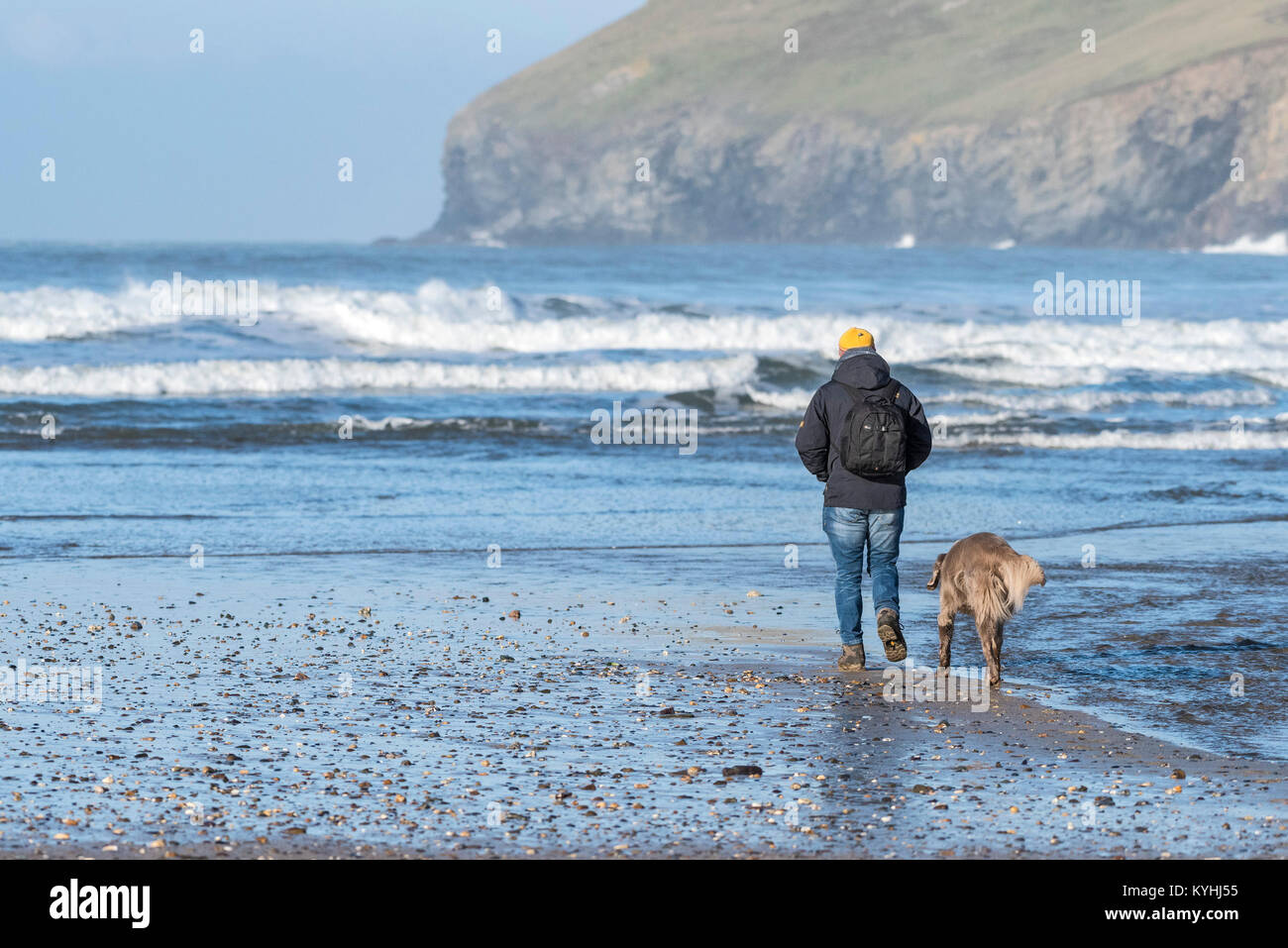 Polzeath - ein Wanderer und seinem Hund auf Polzeath Strand an der Küste von North Cornwall. Stockfoto