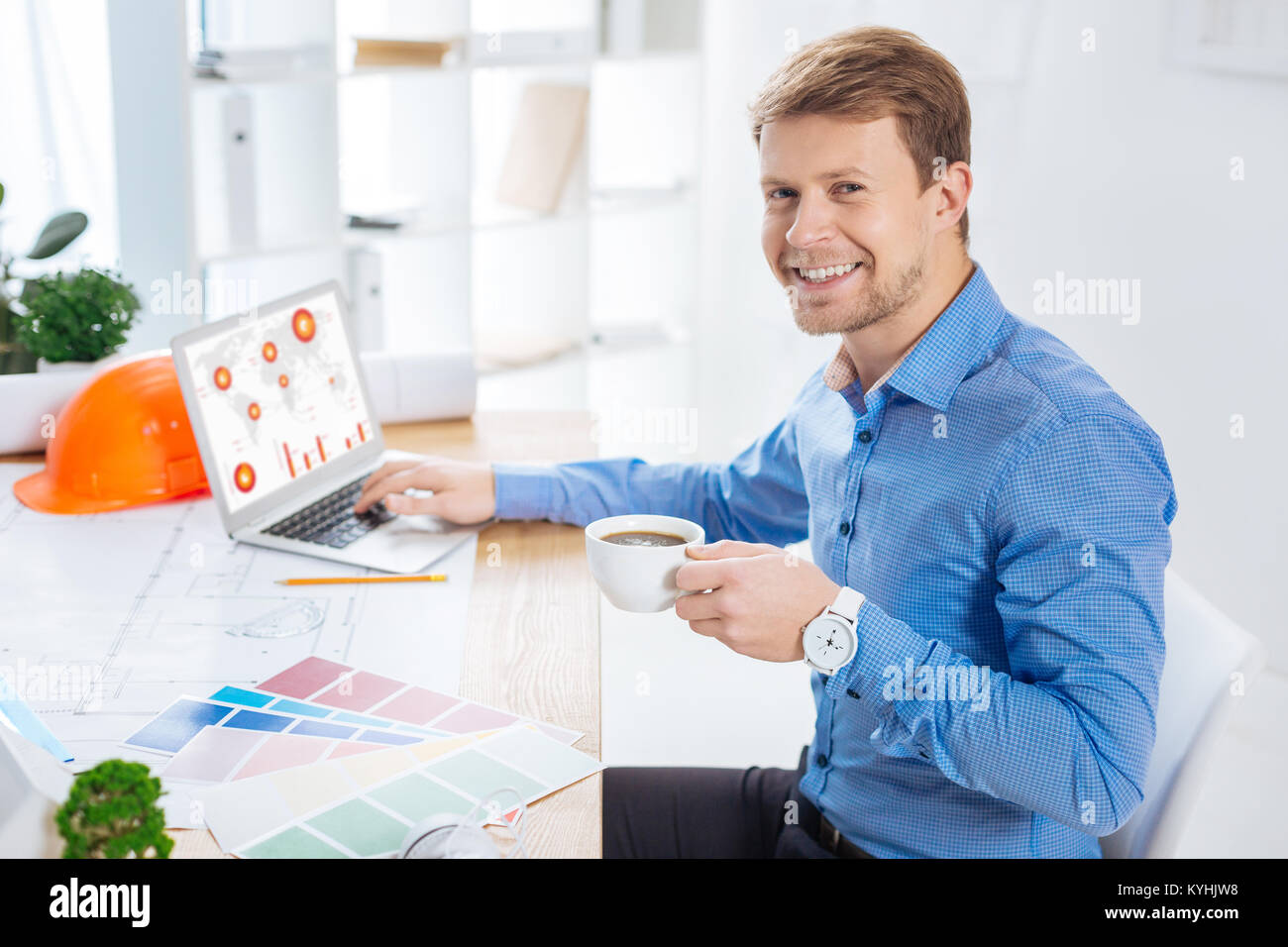 Fröhlicher Mann lächelnd beim Sitzen mit einer Tasse Kaffee Stockfoto