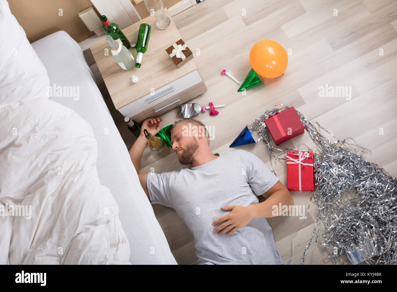 Menschen schlafen auf Versaut Hartholzboden mit Bierflaschen auf dem Nachttisch Stockfoto