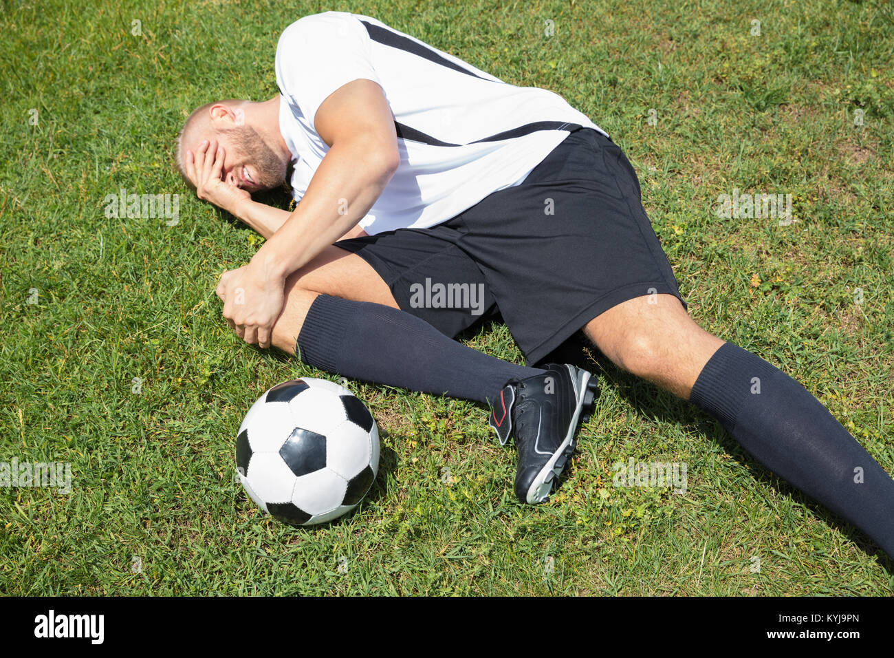 Nahaufnahme der männlichen Fußball-Spieler Leiden Knieverletzung liegen auf Feld Stockfoto