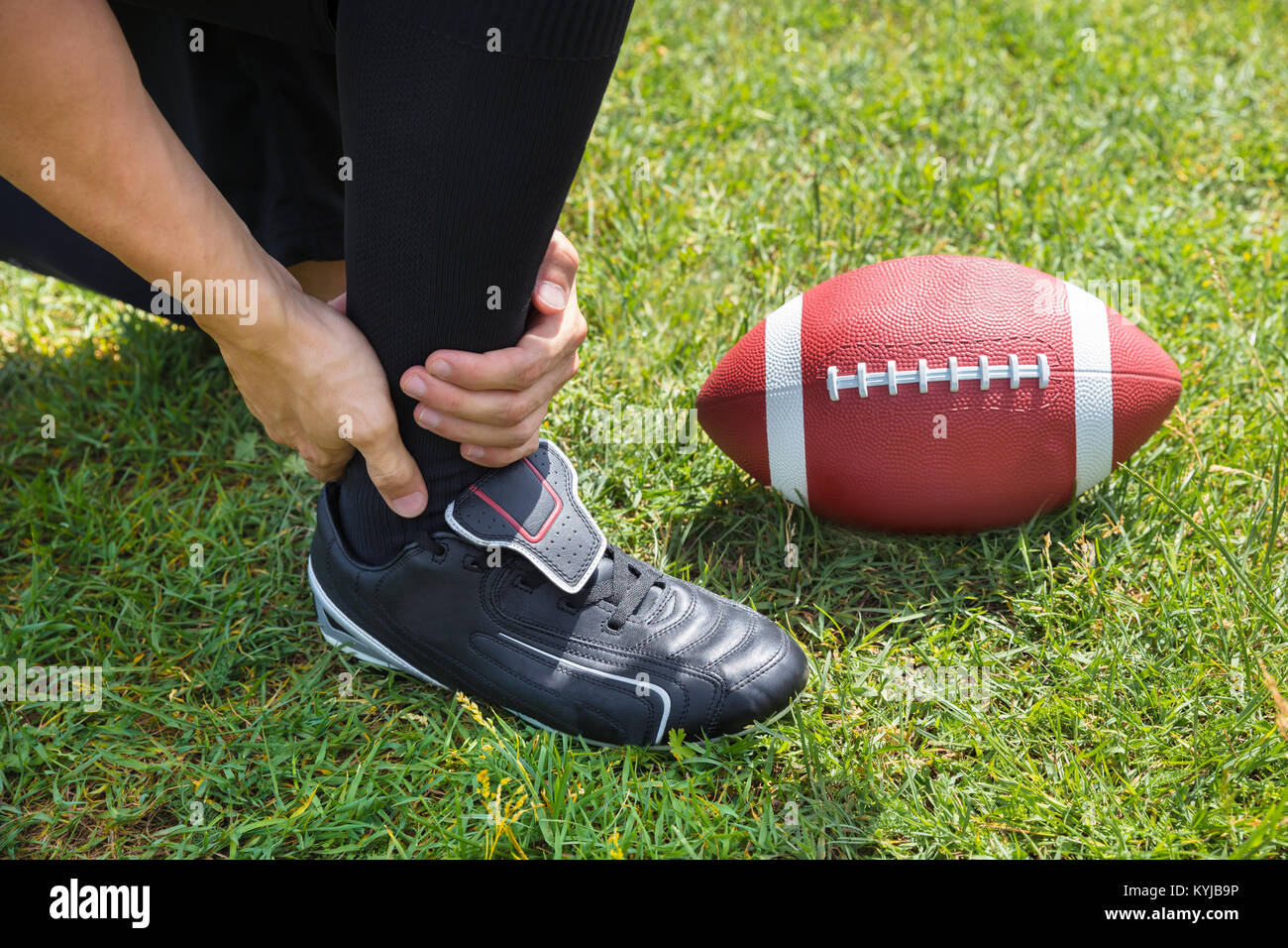 Erhöhten Blick auf American Football Player mit Schmerzen in seinem Knöchel auf dem Feld Stockfoto