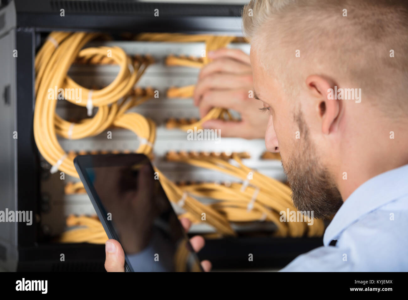 Männliche Techniker arbeiten auf dem Server in einem Rechenzentrum mit Handy Stockfoto