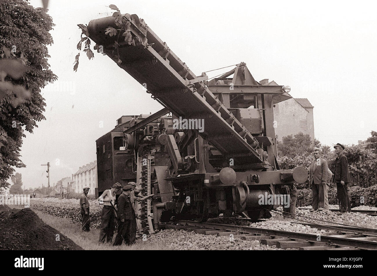 Foto mit einer Martis-Maschine, die zum Ausbreiten von Kies auf einem Eisenbahndamm in Maribor verwendet wurde, 1958, mit Industrie- und Verkehrsinfrastruktur. Stockfoto