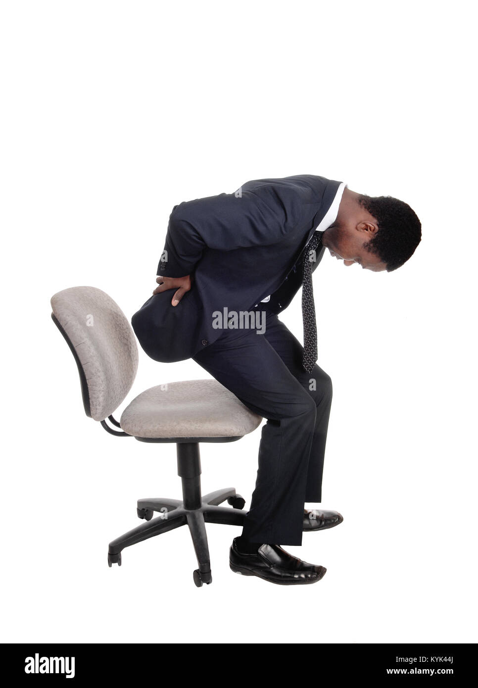 Ein junger Geschäftsmann im Anzug Aufstehen aus seinem Bürostuhl Rücken für Rückenschmerzen, auf weißem Hintergrund Holding Stockfoto