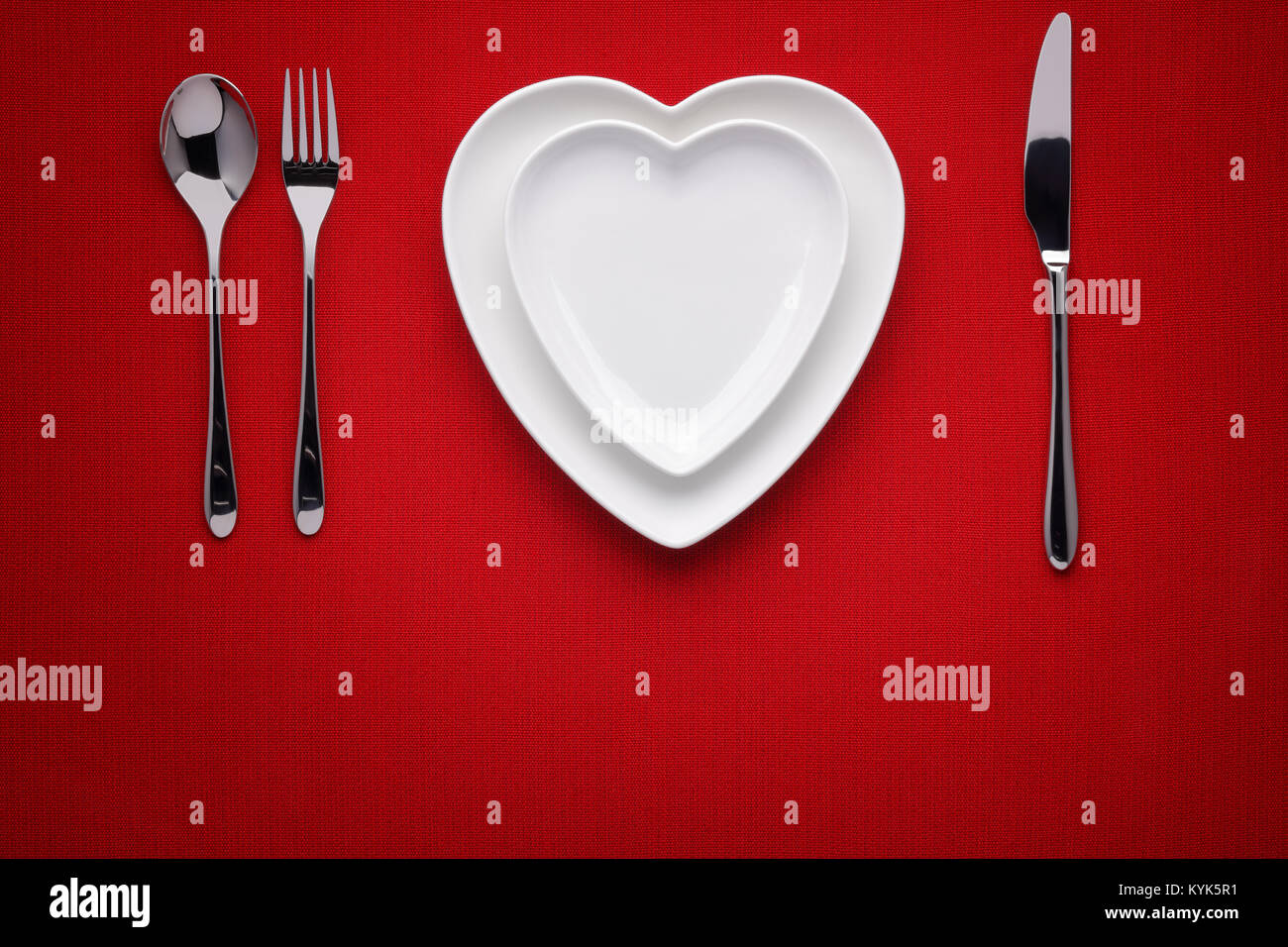 Platte in Form von Herzen, Tabelle Messer und Gabel auf rot Stockfoto
