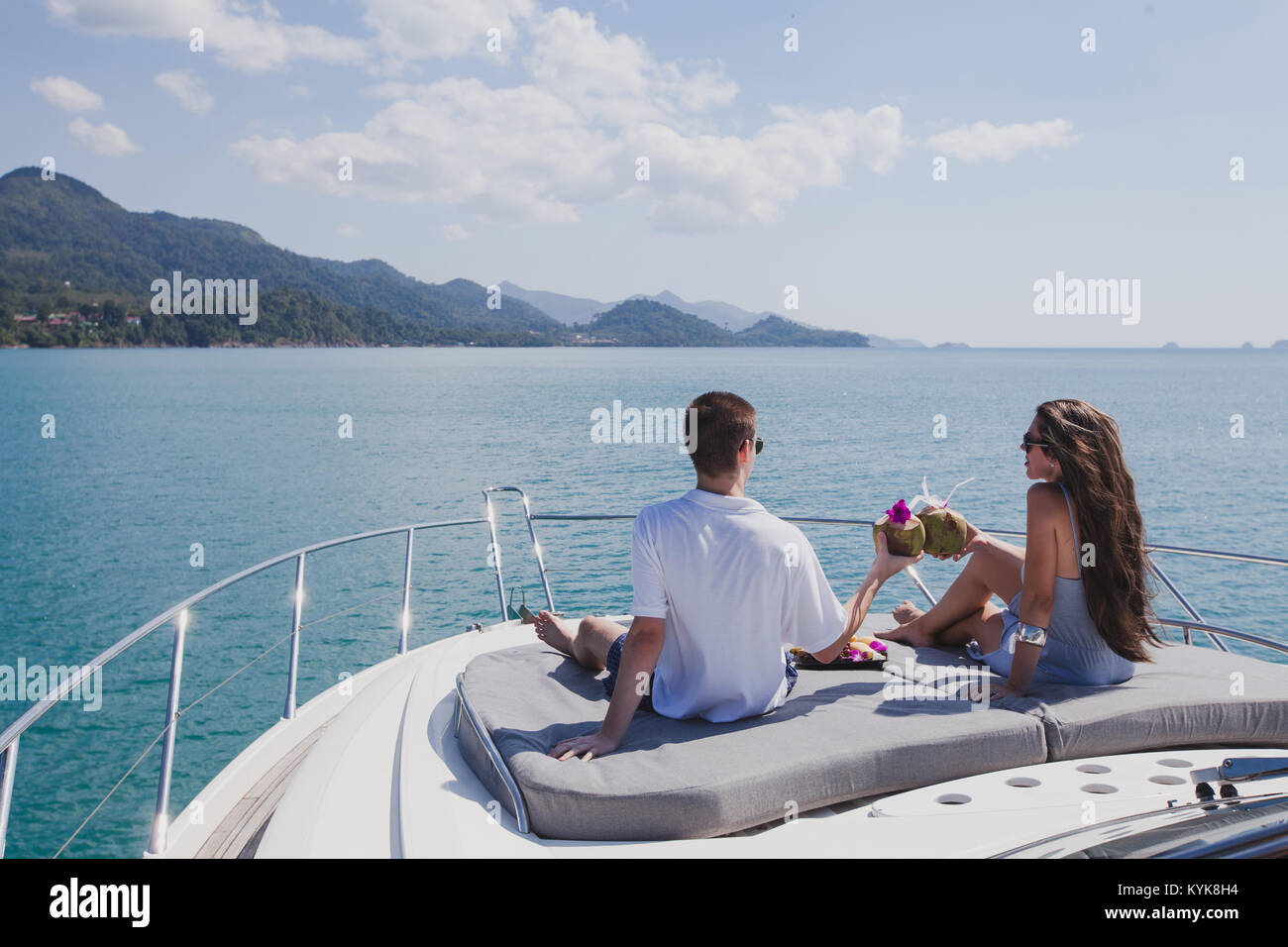 Paar beim Flitterwochen an Bord der luxuriösen Yacht, luxuriöse Yacht in tropischen Meer, Mann und Frau trinkt Kokosnüsse und Entspannen Stockfoto