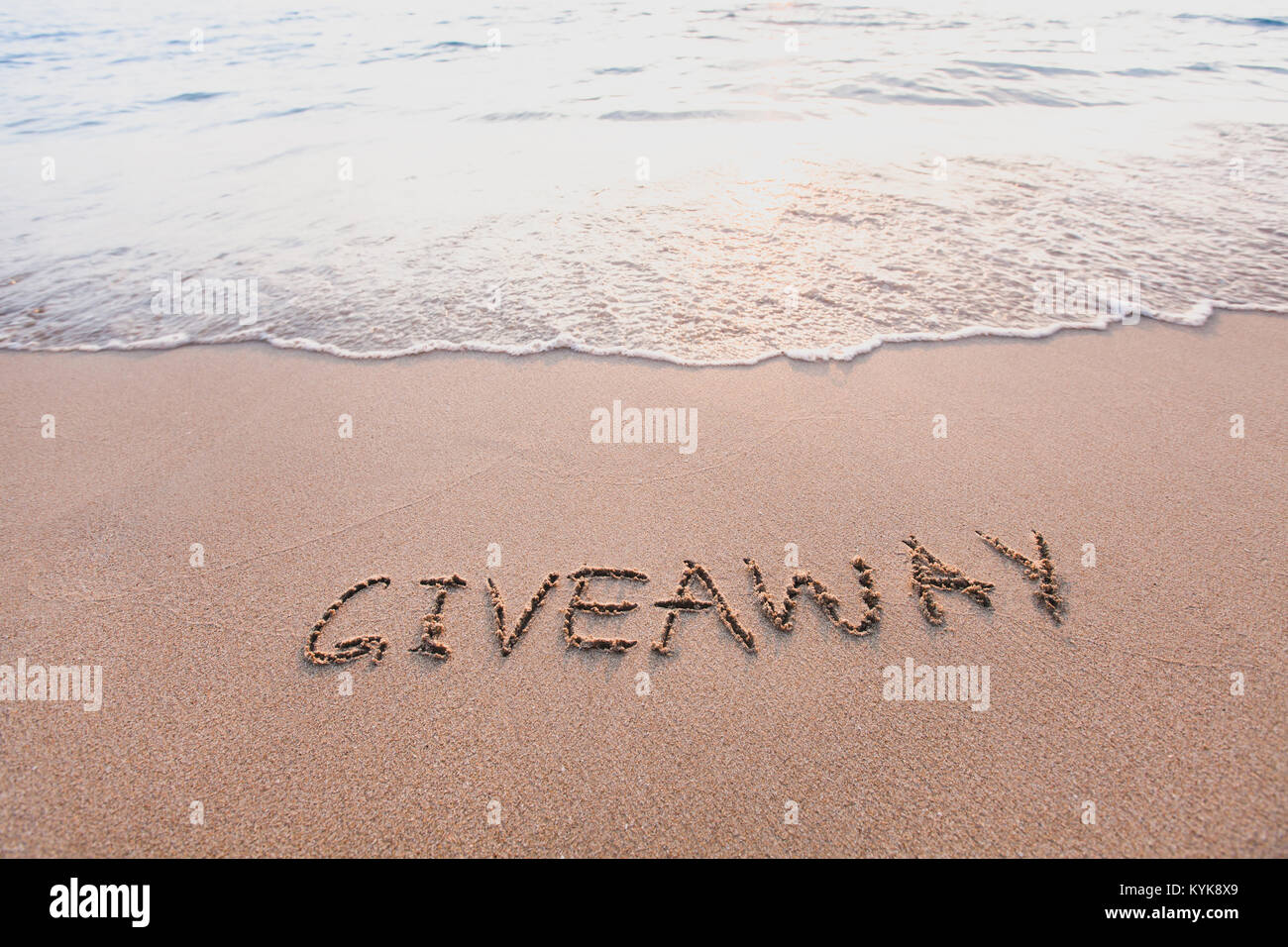 Give-away, Wort Meldung am Sand geschrieben Stockfoto