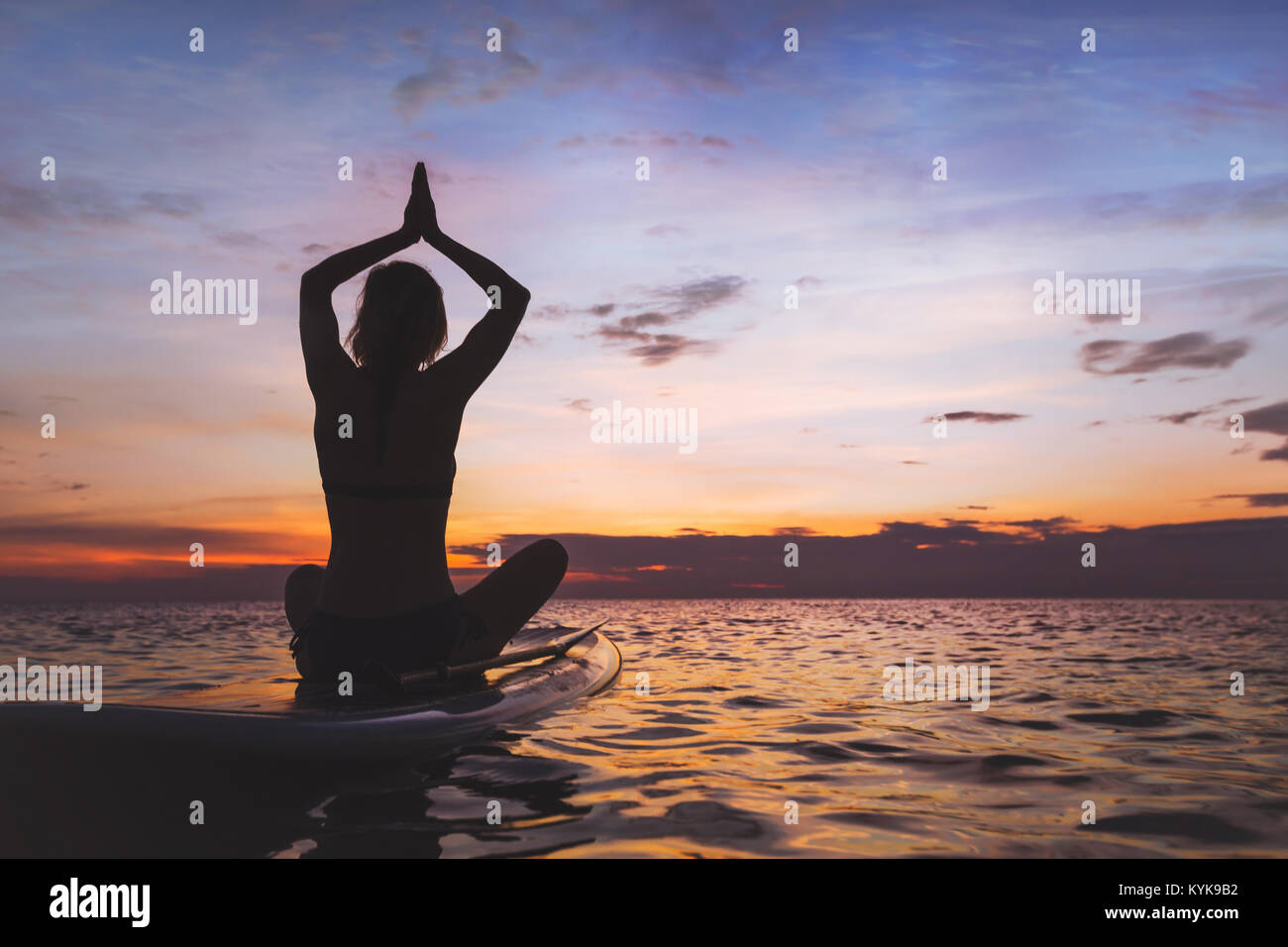 Yoga auf sup Board, Silhouette der Frau am Strand Stockfoto