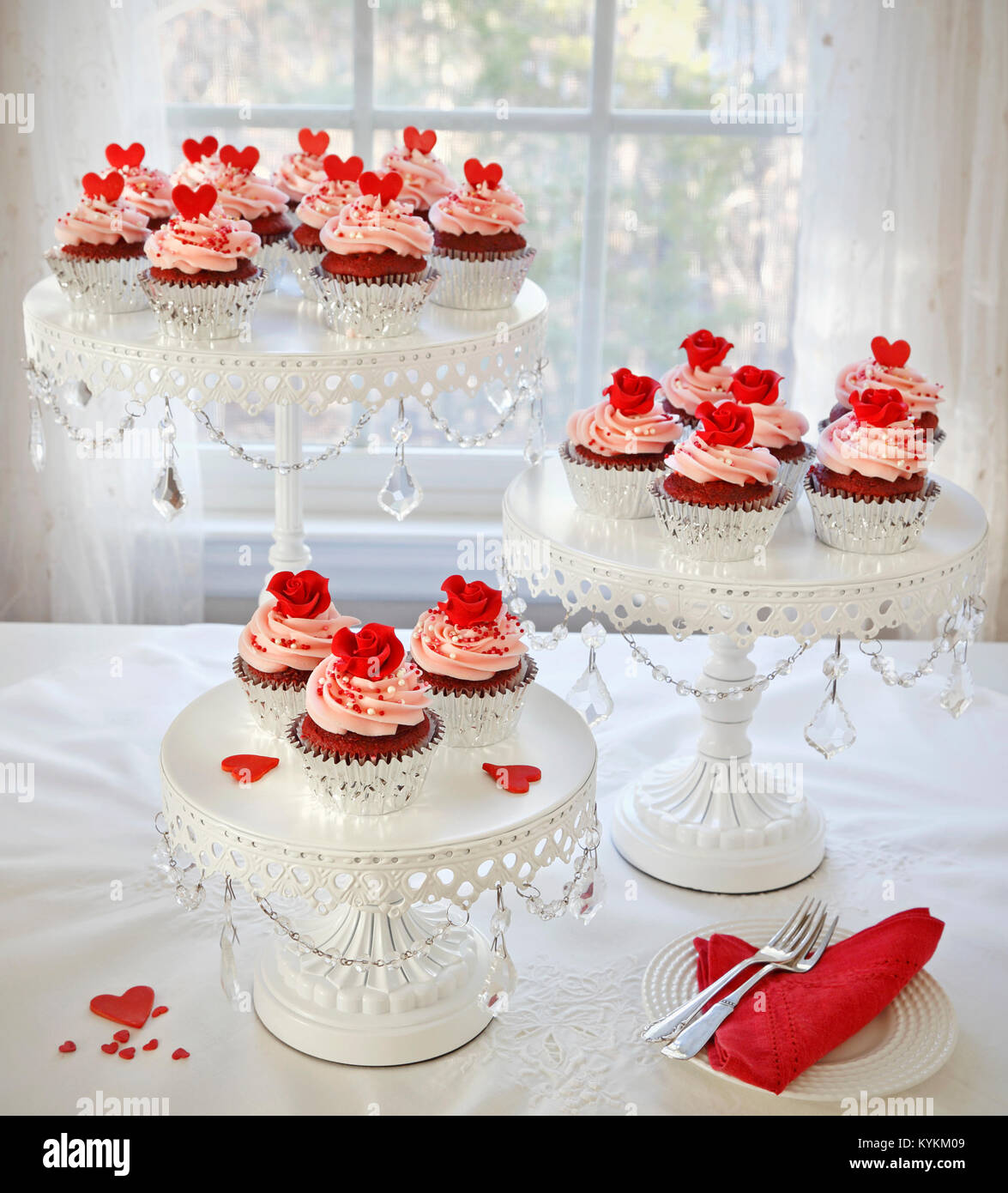 Cupcakes. Red velvet Cupcakes, dekoriert mit roten Rosen und Herzen auf 3-tier cakestand. Stockfoto