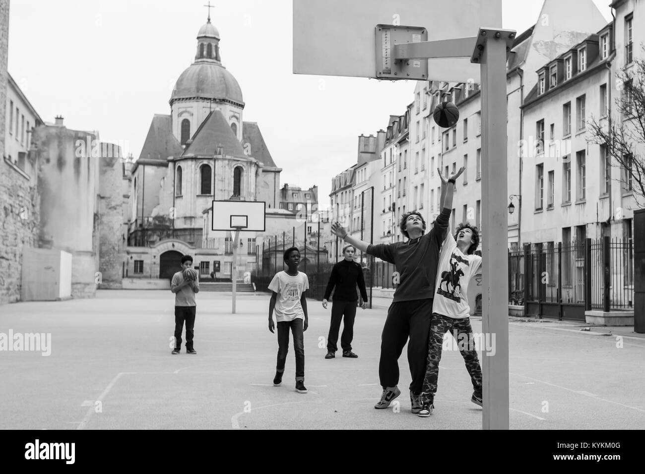 PARIS - Dec 30, 2013: Unbekannter Jungen spielen Basketball in einem offenen Raum zwischen Gebäuden in einer historischen Umgebung. Die Verwendung der Basketballkörbe Stockfoto