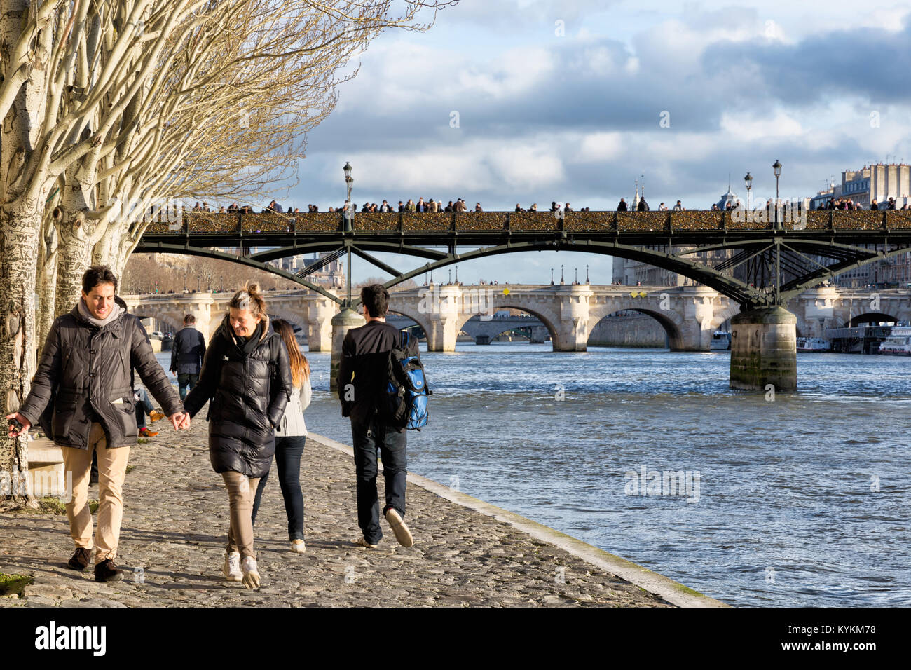 Paris, Frankreich, Paare Spaziergang unter alten Bäumen entlang der Seine. Oben ist die berühmte Brücke bedeckt mit Liebe Schlösser, die später entfernt wurden. Stockfoto