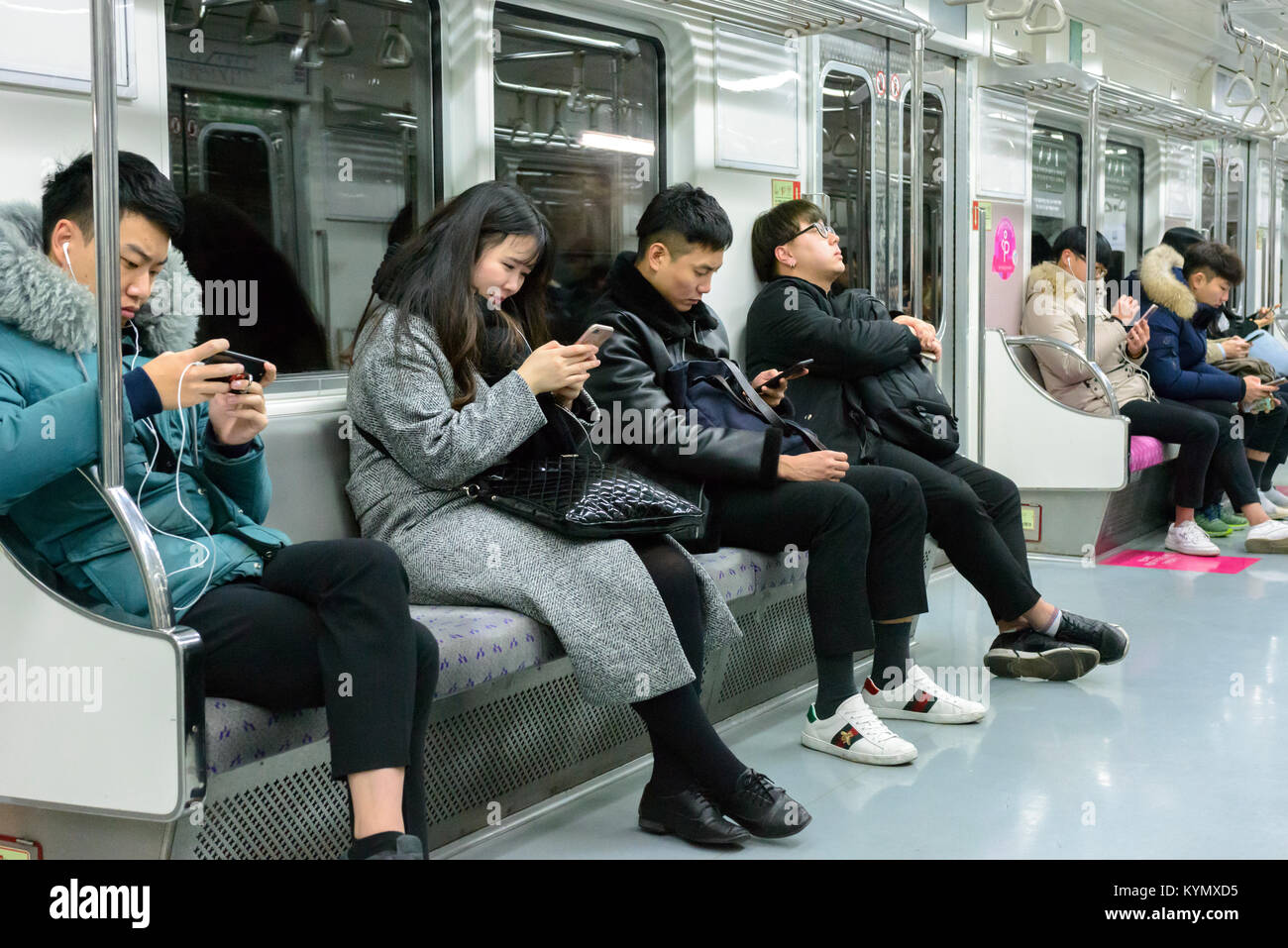 Pendler auf der Seoul u-bahn in Mobiltelefonen vertieft Stockfoto