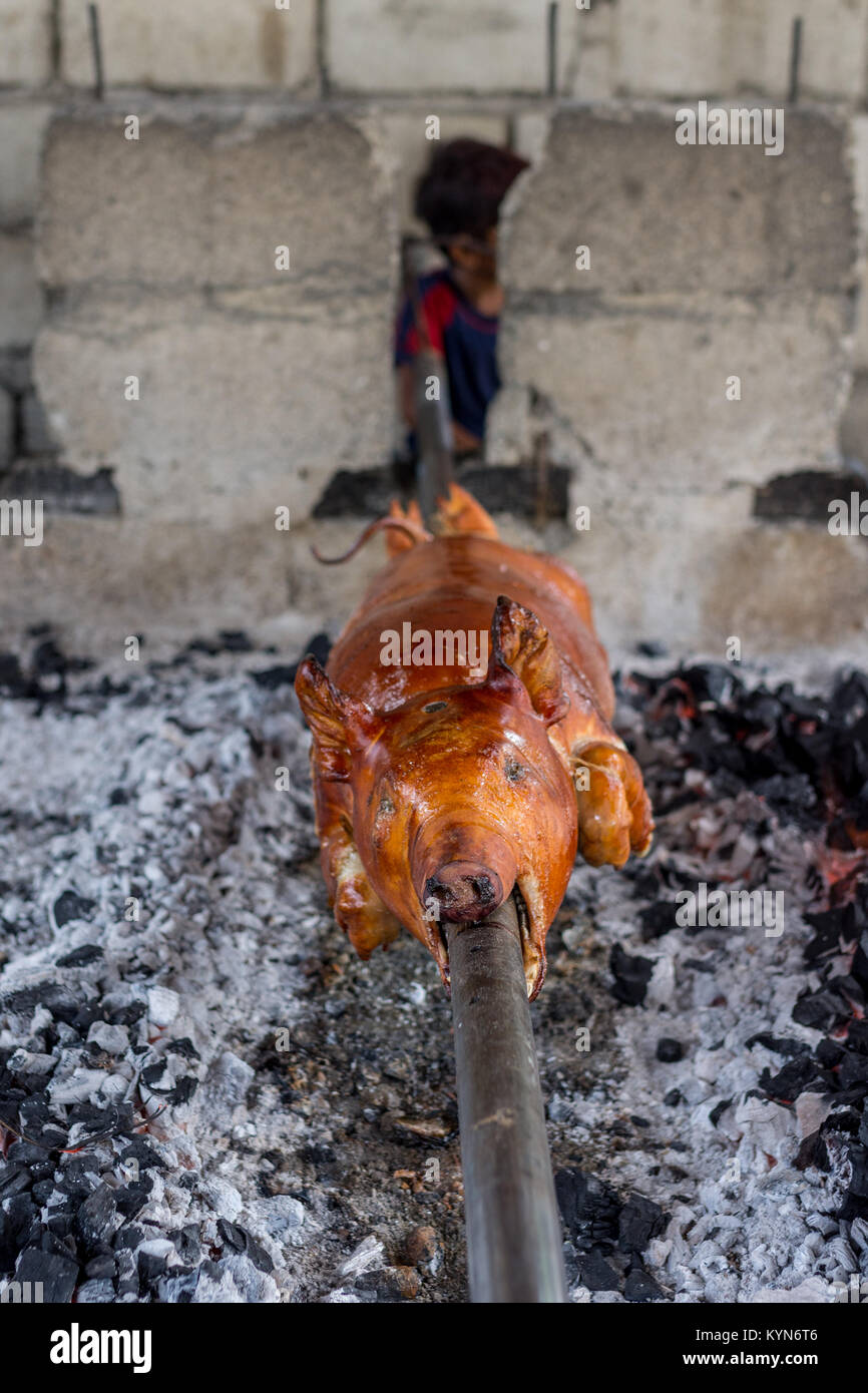 Ein ganzes Schwein gekocht wird und die Hand umgedreht Holzkohle Glut, die philippinische Gericht Lechon mit Vordergrund Fokus Schärfentiefe zu erstellen. Stockfoto