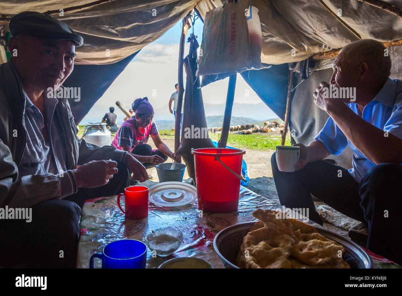 KAZARMAN, Kirgisistan - 15. August: Frau kumis, gegorene Stutenmilch, von einem Schaf Haut in einer einfachen Unterkunft zu zwei Männern. August 2016 Stockfoto