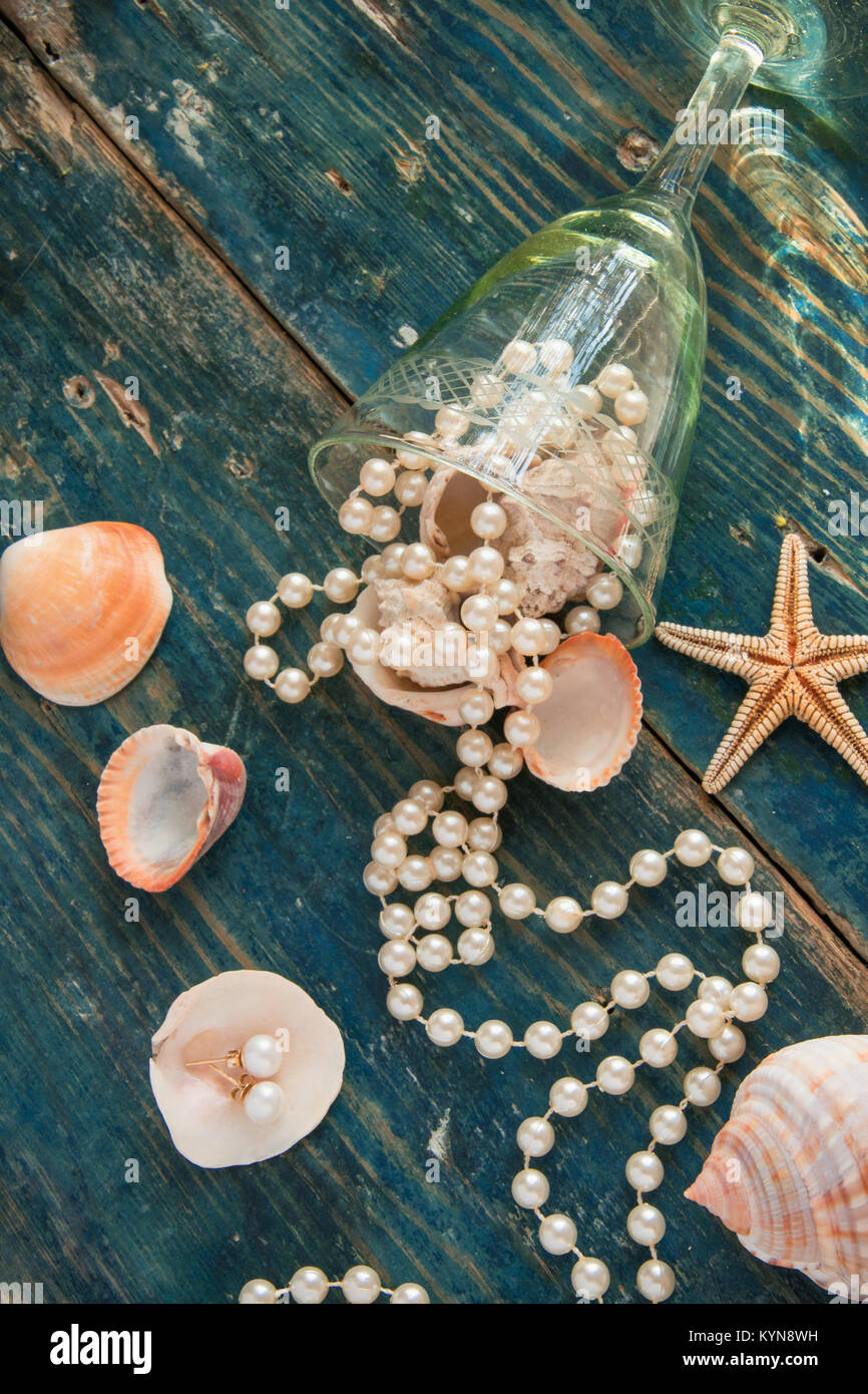 Der piratenschatz - weiße Perlen und Muscheln auf blauem Hintergrund Holz, Vintage Mode Konzept Stockfoto