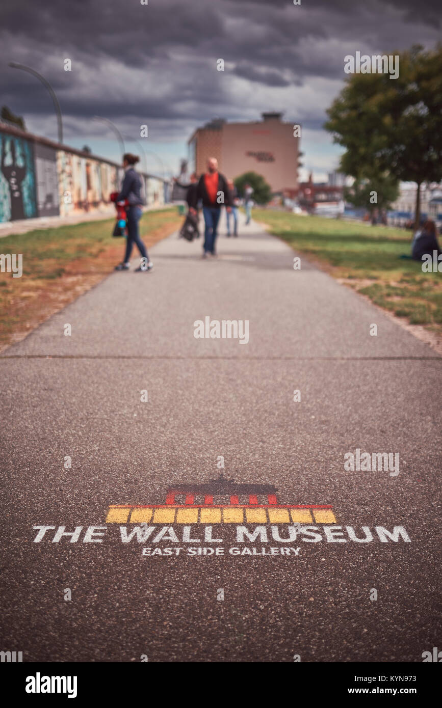 Berlin, Deutschland, Mauer Museum - East Side Gallery, Gehweg mit Museum Namen, Leute, die im Hintergrund von einem bewölkten Tag Stockfoto