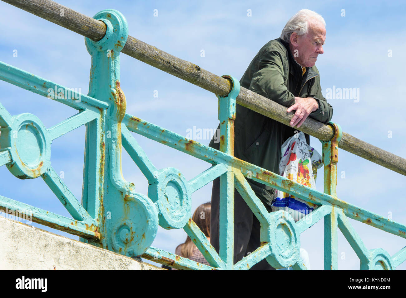 Pensionierter Mann über das Geländer an der Küste von Brighton, Sussex, UK. Stockfoto