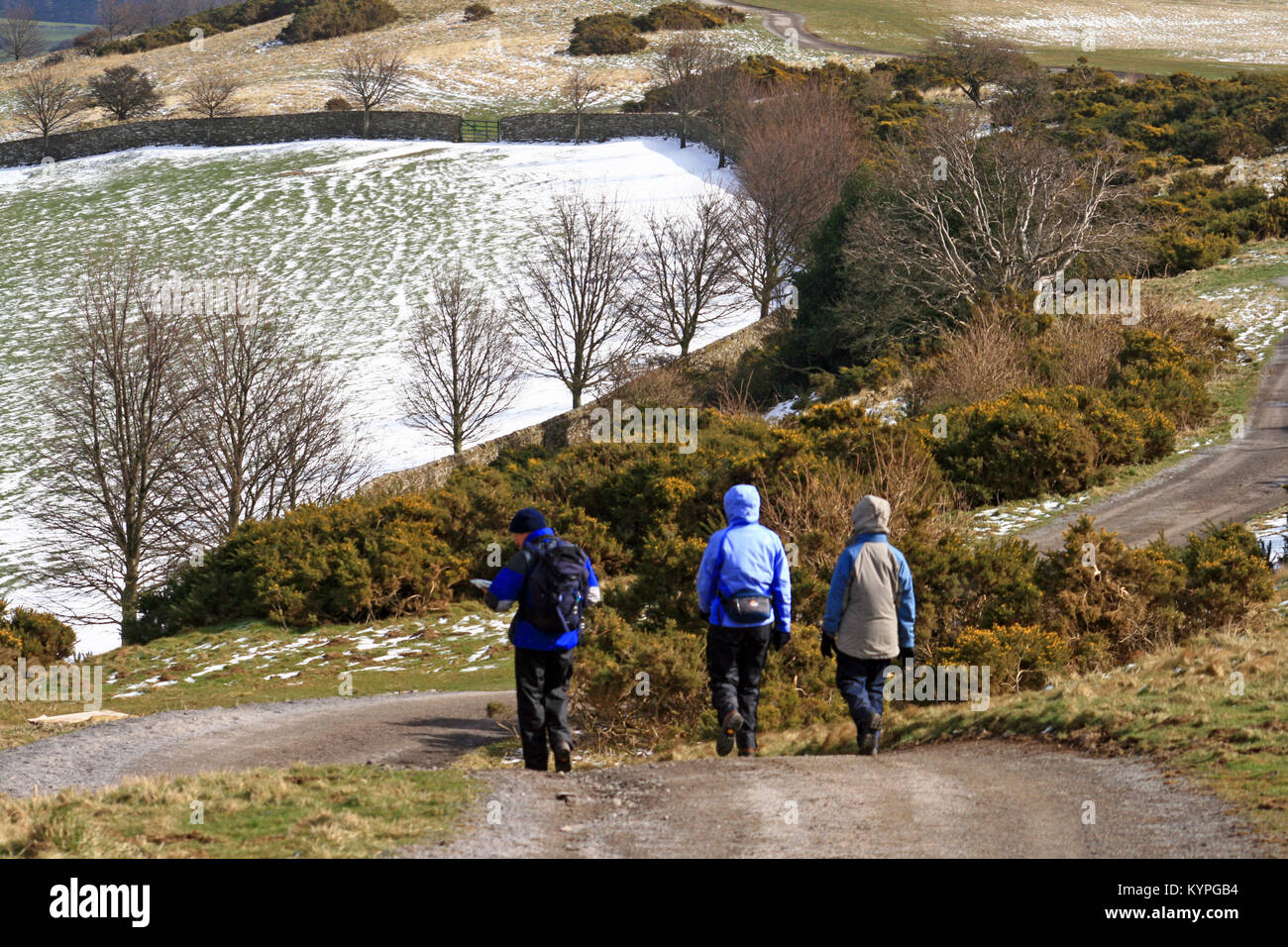 Drei Menschen tragen wasserfeste Kleidung mit Hauben bis zu Fuß in den Bergen von North Yorkshire zwischen Leyburn und Middleham nach einem Schnee Dusche Stockfoto