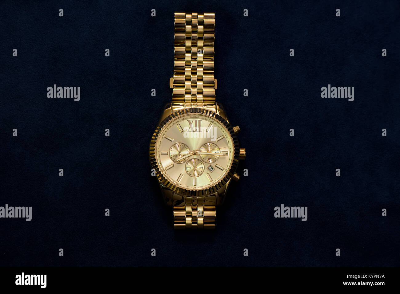 Gold Armbanduhr mit einem gelben Metall Armband auf dunkelblauem Hintergrund, separat Stockfoto