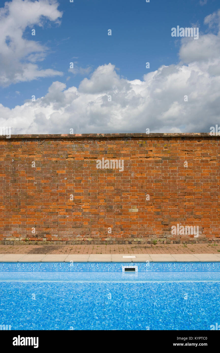 Old Red Brick Wall kontrastierenden mit blauem Himmel und Schwimmbad Stockfoto