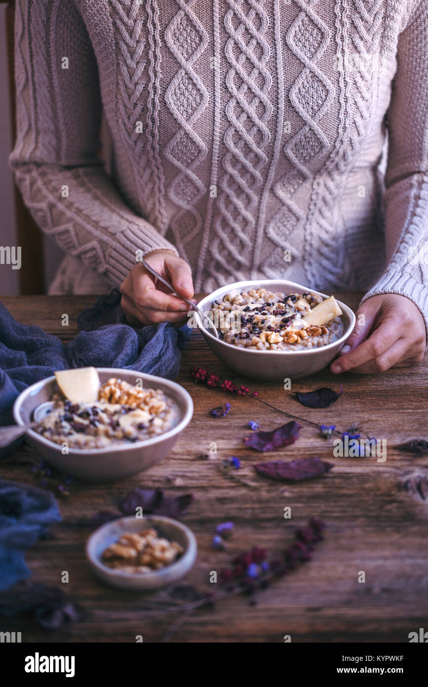 Frau essen apple Buchweizen Brei mit Walnüssen, Cashew Butter überstieg, Äpfel Schichten und Kakao Nibs Stockfoto
