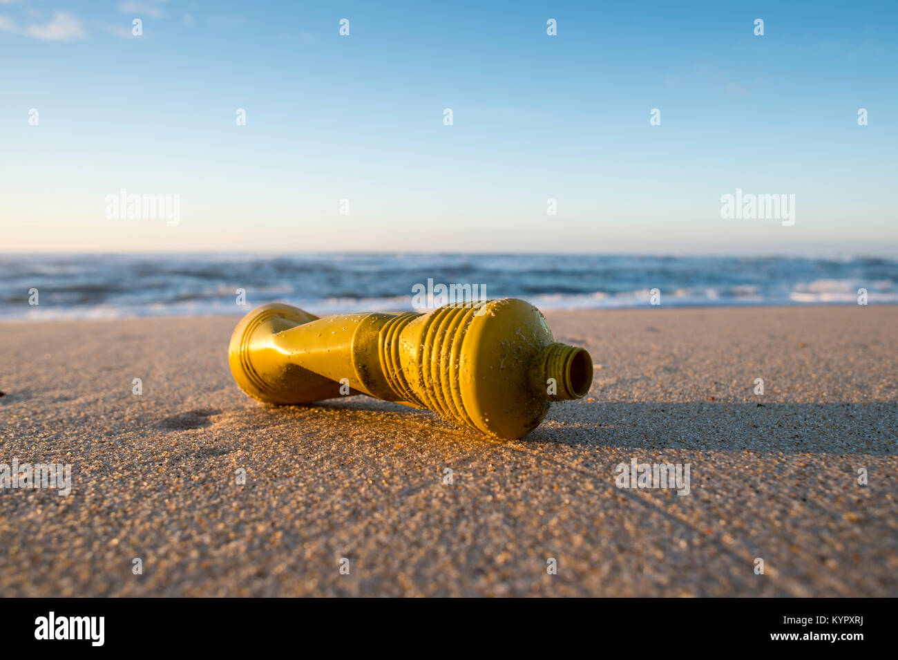 Gelbe Plastikflasche an einem verlassenen Strand, Meer Verschmutzung mit Nicht recyclingfähiger Kunststoff. Stockfoto