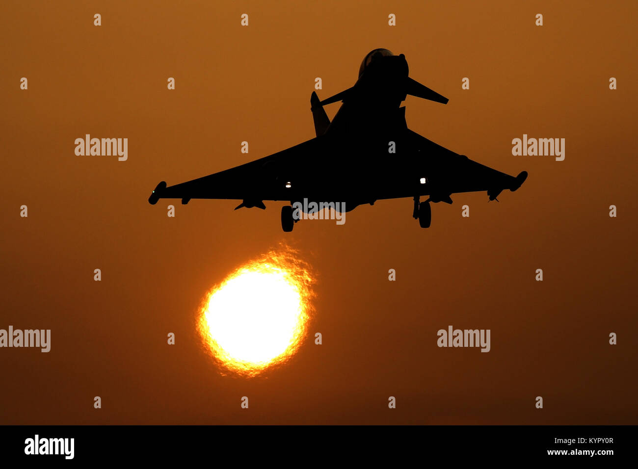 RAF Typhoon silhouetted gegen die untergehende Sonne kehrt in RAF Coningsby an einem nebligen Tag mit der Sonne durch die Jets Auspuff verzerrt. Stockfoto