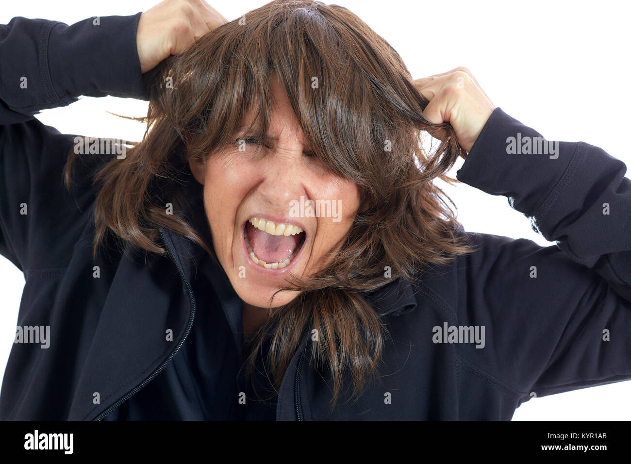 Attraktive Frau mittleren Alters ziehen ihr braunes Haar und schreien auf Weiß isoliert Stockfoto