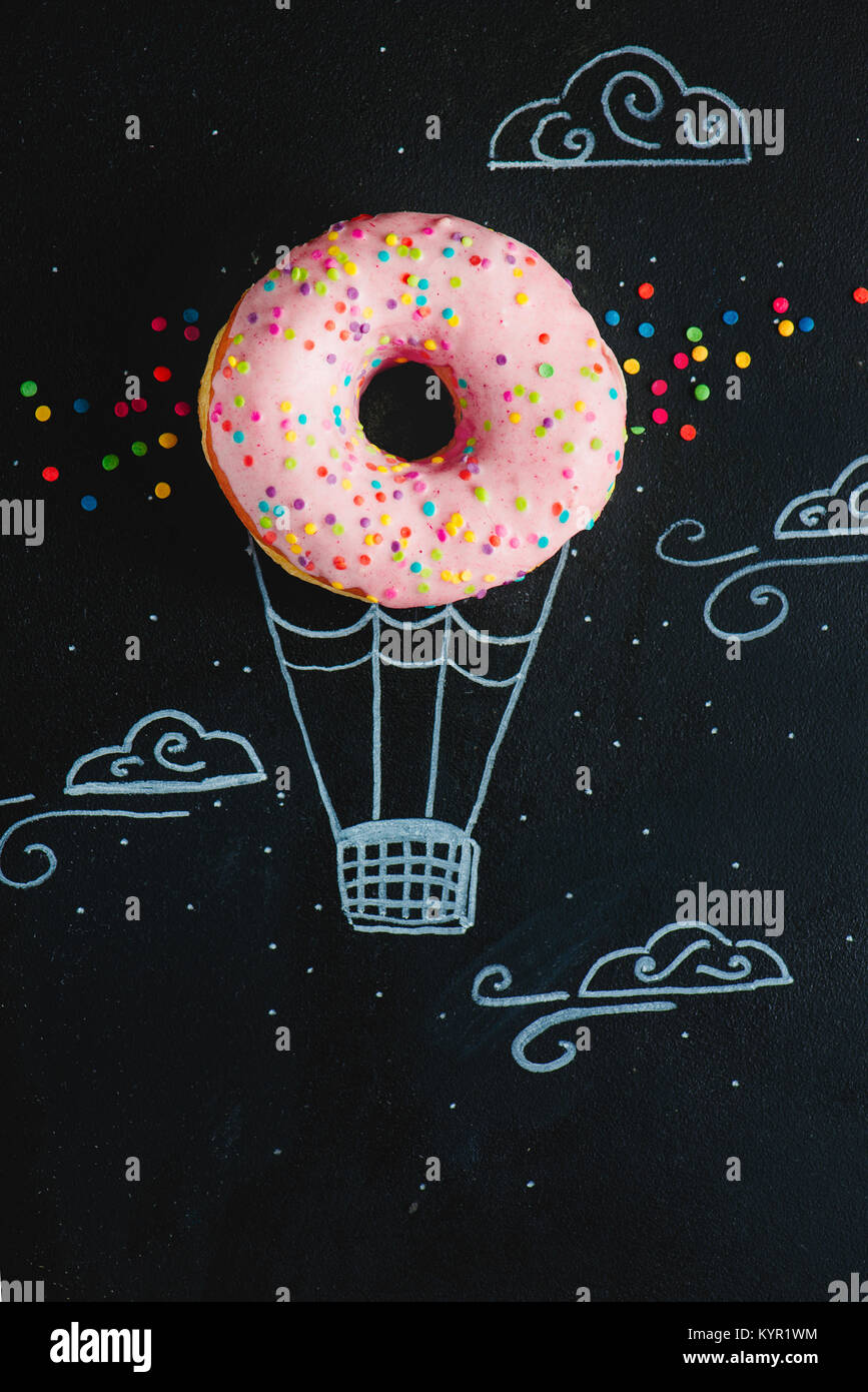 Rosa glasierten Krapfen mit Kreide Zeichnung von Hot Air Balloon. Kreatives Konzept. Low Key essen Fotografie. Stockfoto