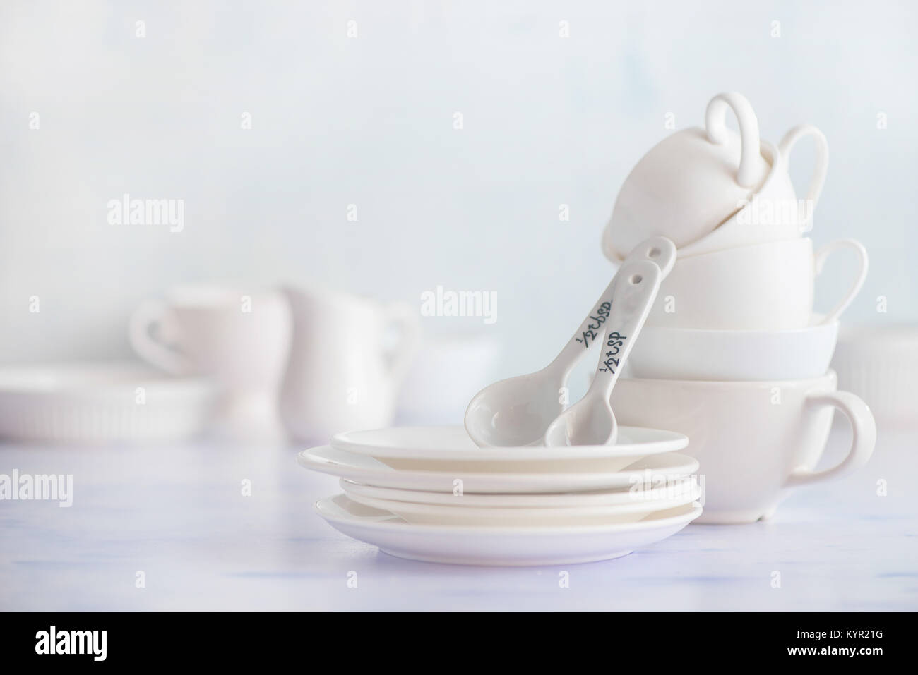 Stapel von teatime Geschirr. Porzellan Tassen und Untertassen auf weißem Holz- Hintergrund. High key Essen Fotografie. Stockfoto