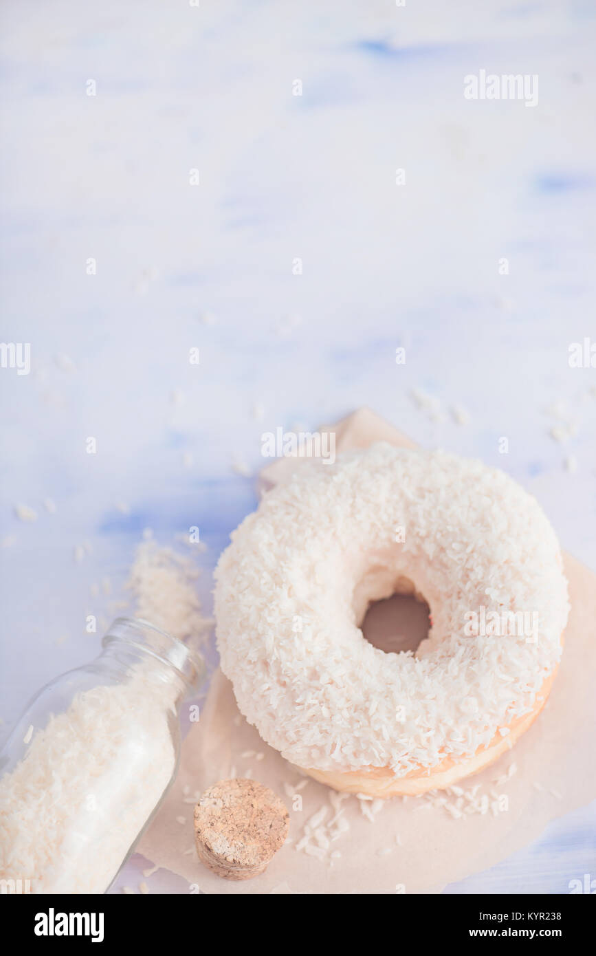 Kokoscreme gefüllt weiss Donut mit Kokosnuss Topping auf Backen Wachspapier. High key Essen Fotografie. Flasche Kokos Chips Stockfoto