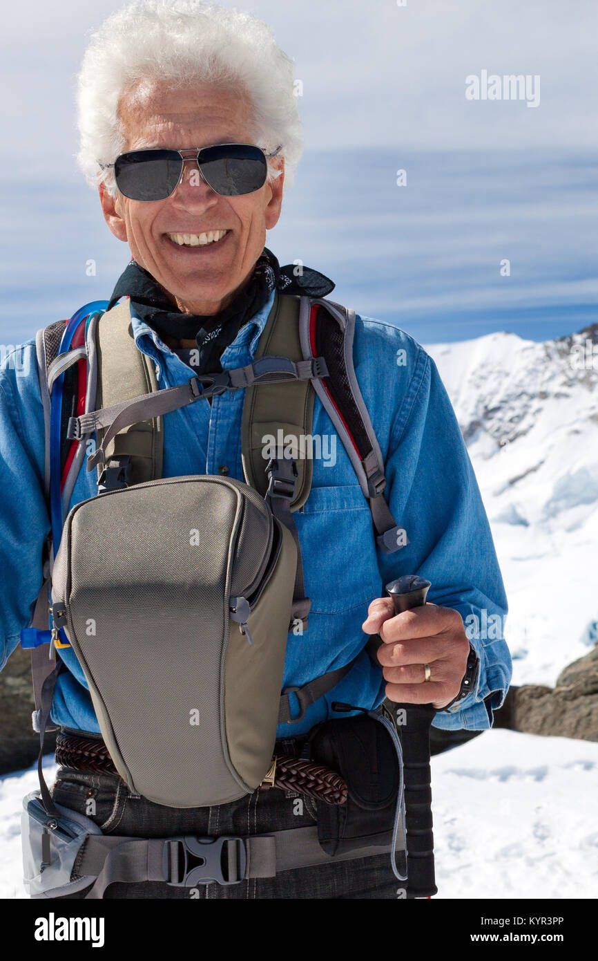 Ältere Menschen Wandern in den Bergen. Abenteuer Reisen in den Schweizer Alpen. Mit Sonnenbrille, Kamera Tasche, Trekking Stöcke. Stockfoto