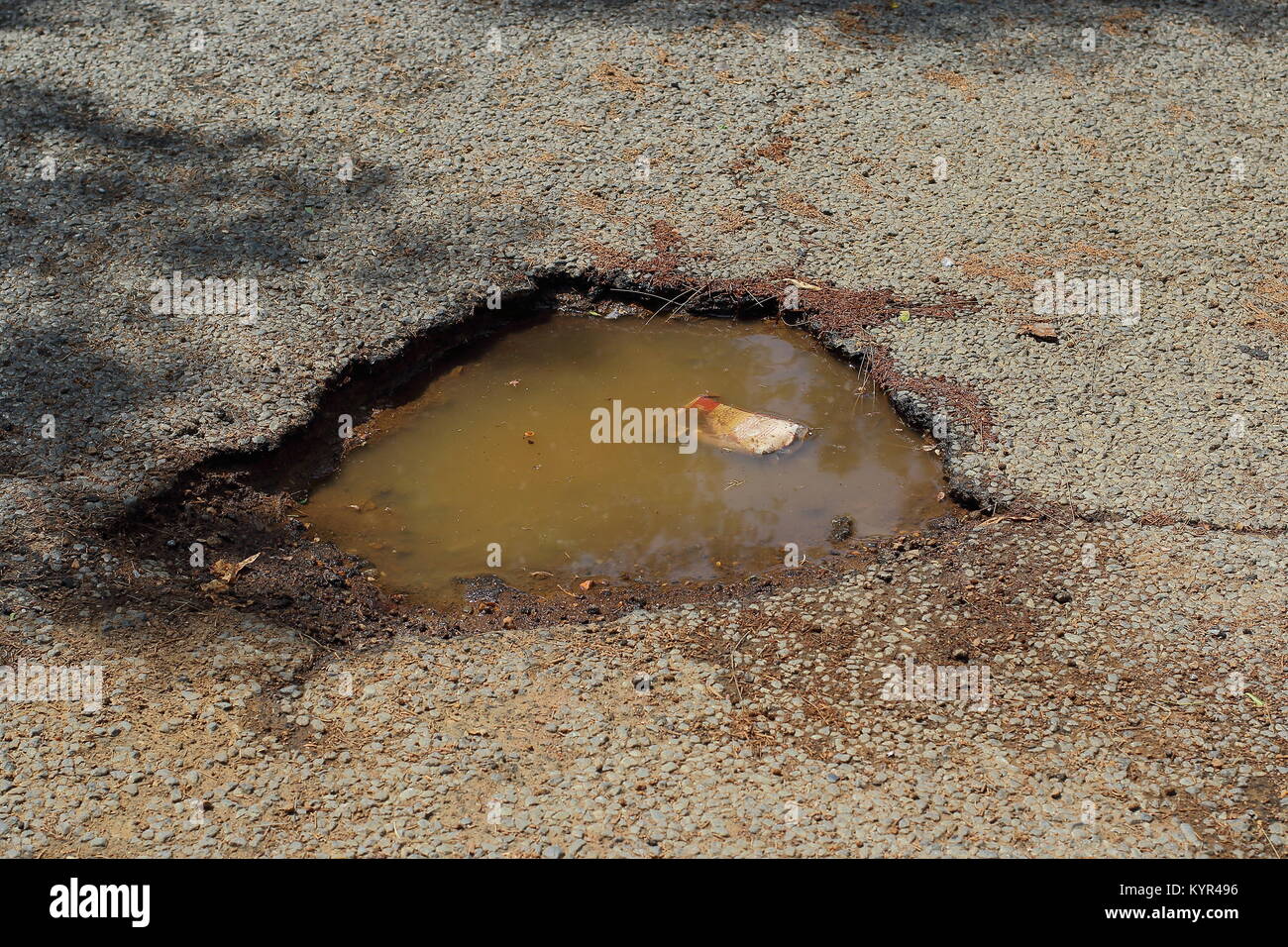 Schlagloch mit Wasser gefüllt in die Oberfläche einer Teerstraße, Bild im Querformat mit Kopie Raum Stockfoto