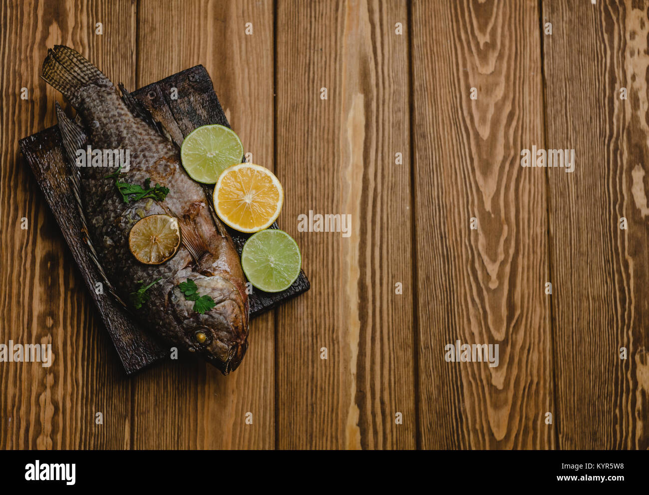 Ansicht von oben gebackenen Fisch mit Zitrone und Kräutern auf Holzbrett Stockfoto