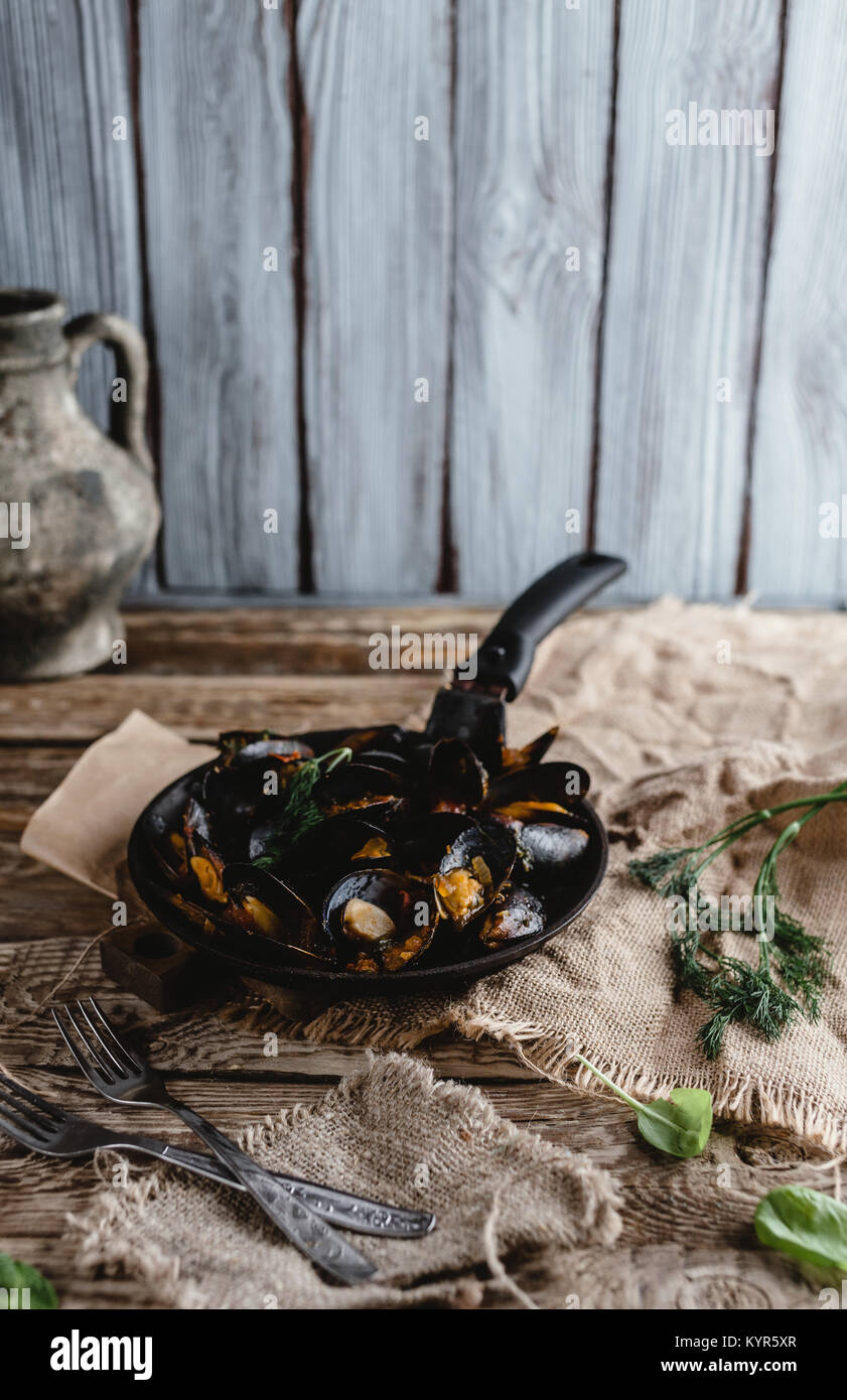 Gourmet gebratene Muscheln mit Muscheln auf Pfanne und Gabeln auf Tisch Stockfoto