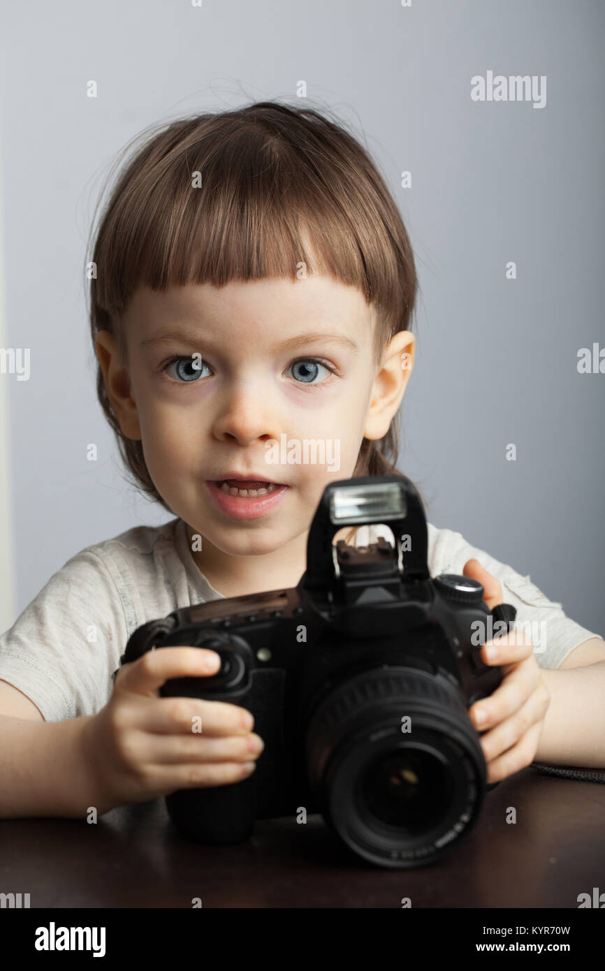 Schönes Kind in eine professionelle Kamera. Kleiner Junge mit langen blonden Haaren fotografieren im Studio Stockfoto