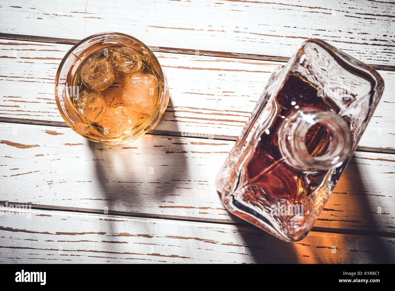 Whiskey Flasche und Whiskey Glas mit Eiswürfeln auf weissem Holztisch Stockfoto