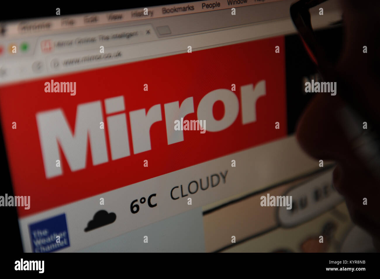 Eine Frau schaut in den Spiegel online Zeitung Stockfoto